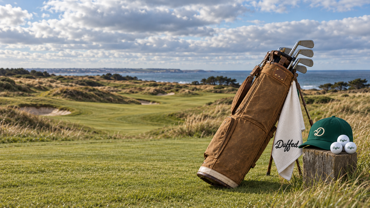 Duffed Fairway D cap, white towel and Forest Script balls beside a coastal fairway