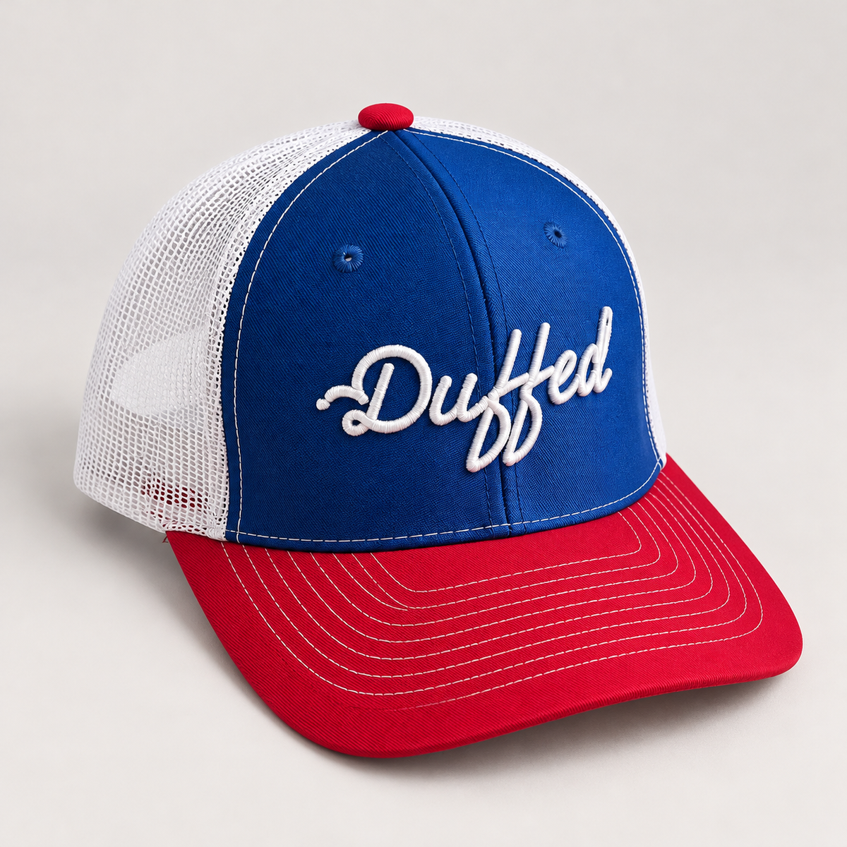 Duffed Stateside Script Trucker in royal blue, red and white — studio product photograph